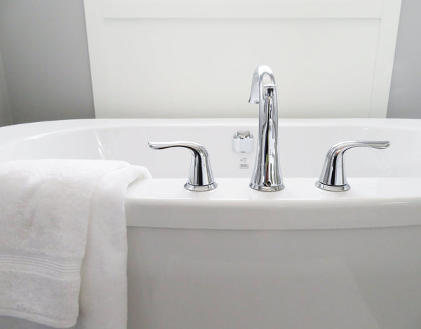 bathtub faucet and white towel draped over edge
