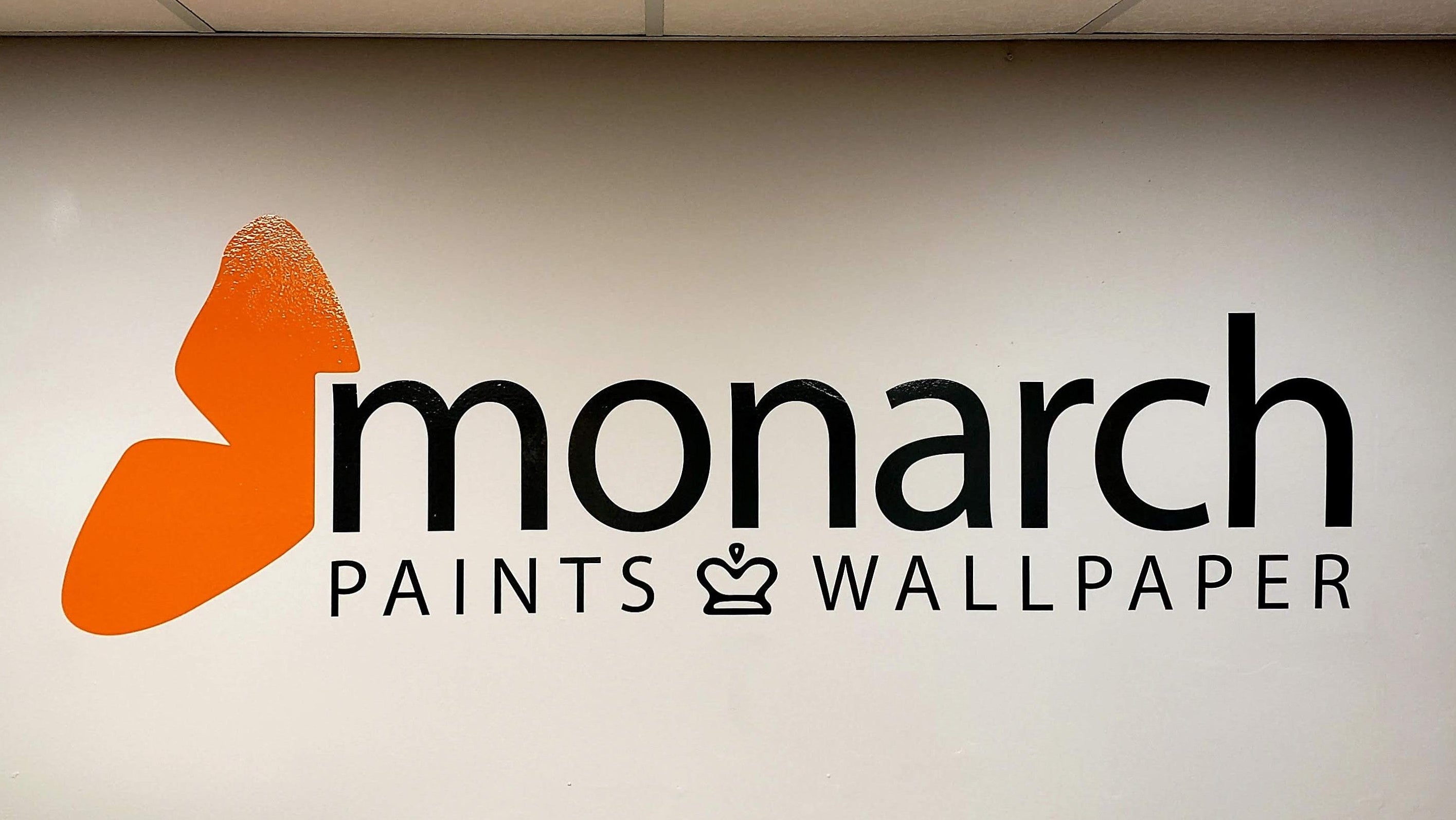 Monarch Paints and Wallpaper logo on a wall in an indoor setting